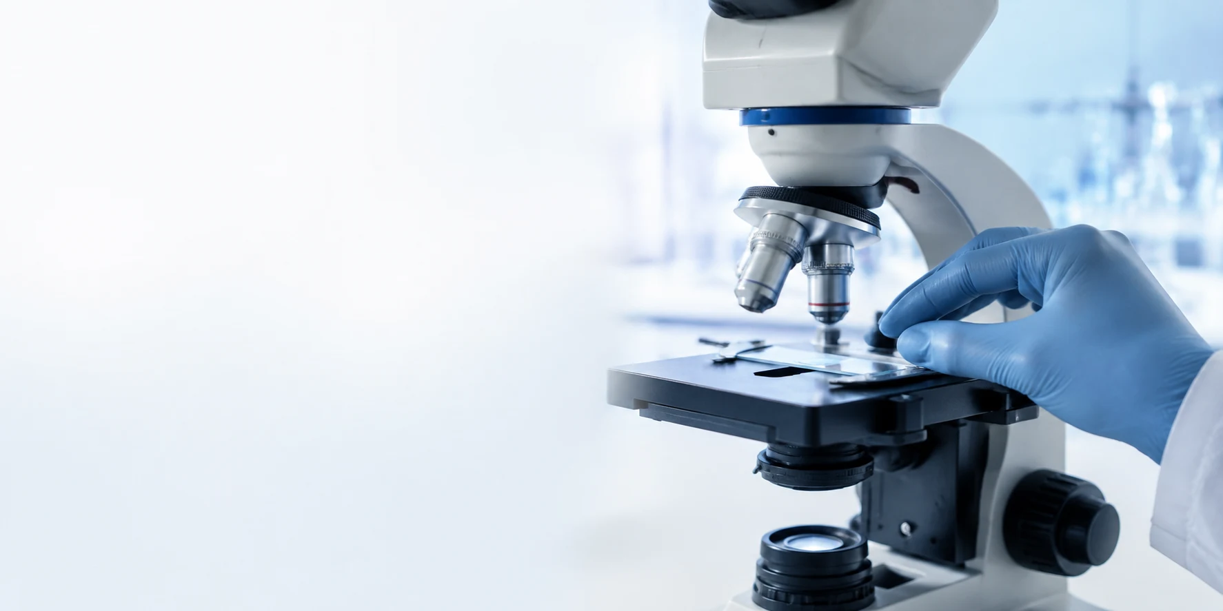 Illustrative laboratory scene with a microscope and a gloved hand preparing a slide